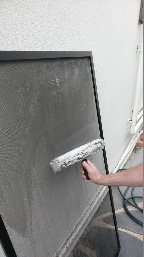 Washing a fly screen panel with a roller brush