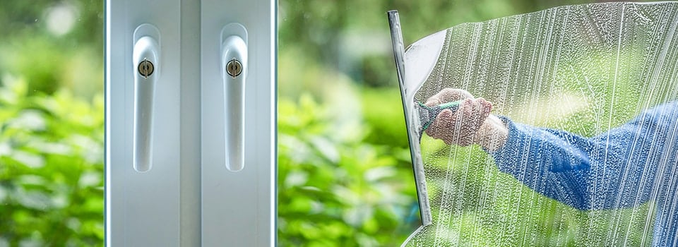 Squeegee gliding over a home window with garden views